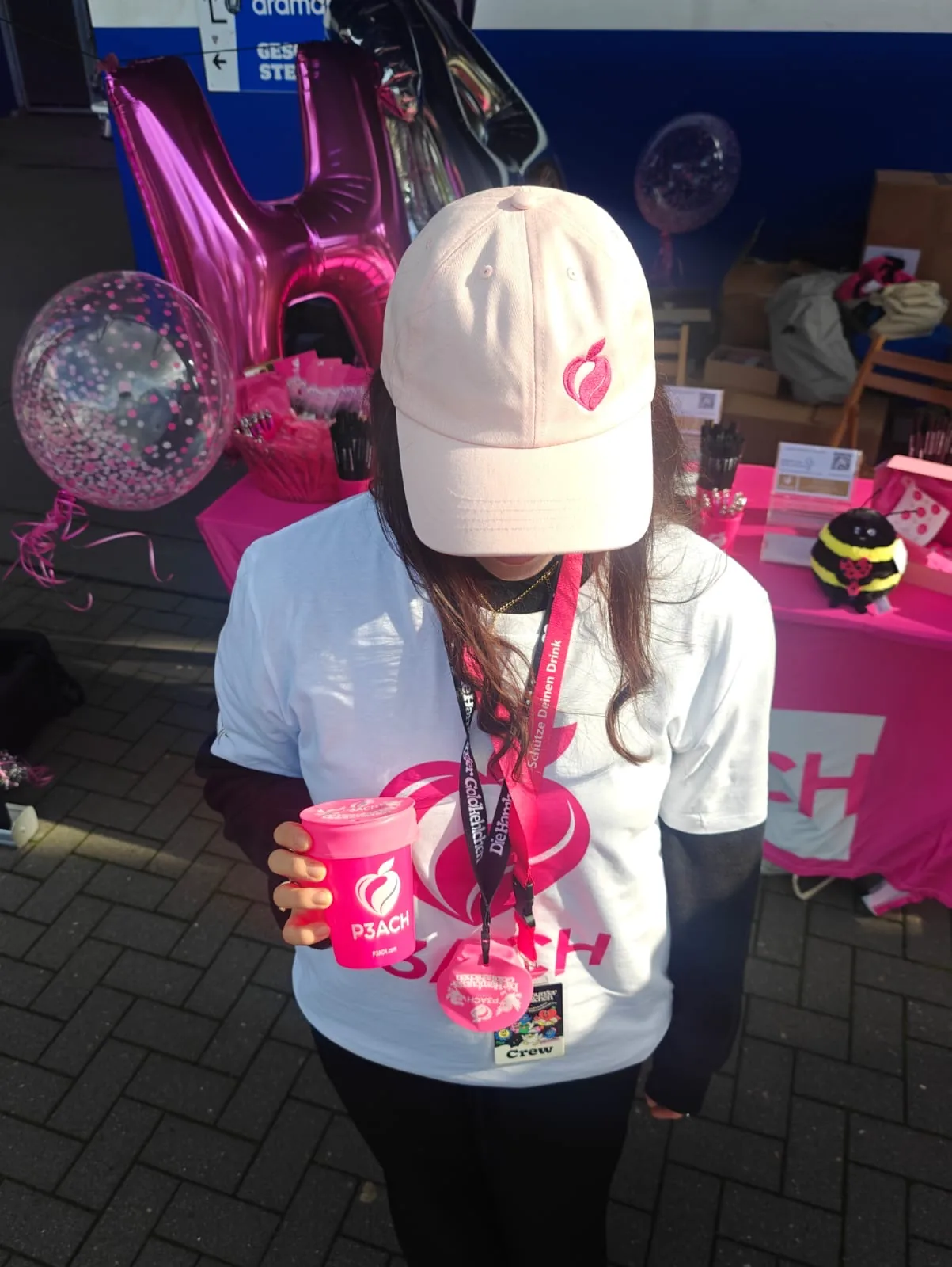 Promoter in a P3ACH cap holding a pink cup with the edition cover at the P3ACH stand