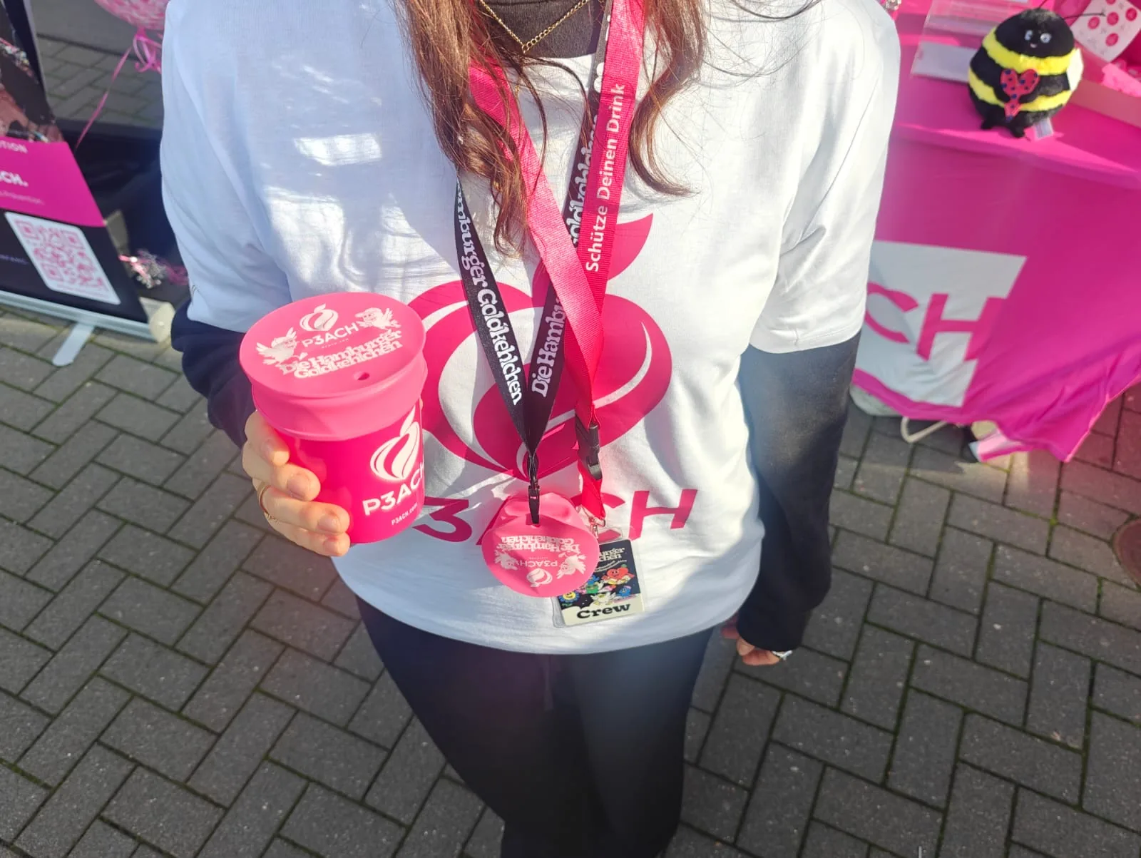 Pink P3ACH cup with the Goldkehlchen edition cover, held by a promoter wearing a P3ACH shirt